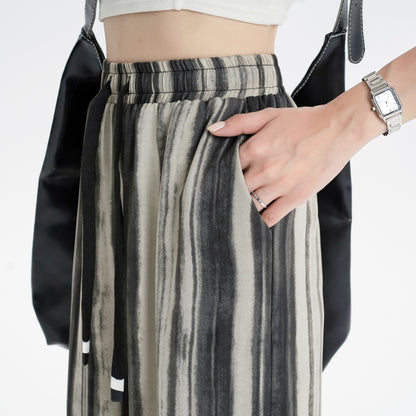 Pantalon ample à taille haute en tissu fluide, à motif tie-dye dans des tons doux, pour une silhouette affinée.