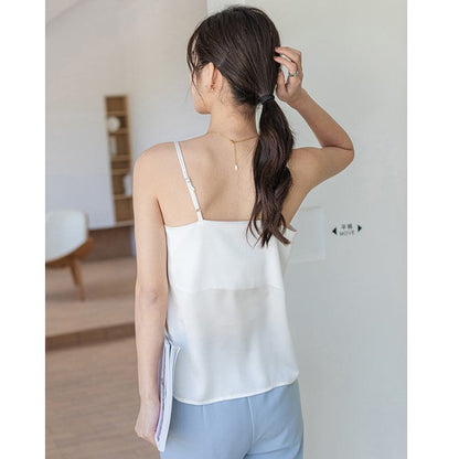 Camiseta sin mangas suelta de seda de acabado satinado y cuello en V blanco, usada como ropa interior fuera de casa.