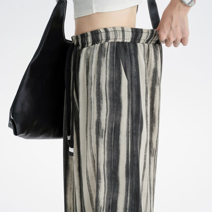 Pantalon ample à taille haute en tissu fluide, à motif tie-dye dans des tons doux, pour une silhouette affinée.